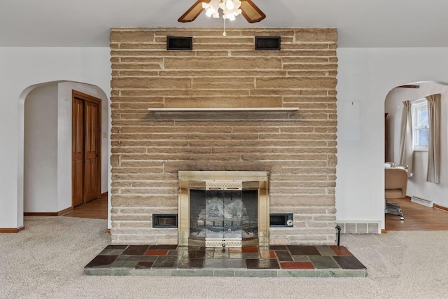 unfurnished living room with arched walkways, carpet, a fireplace, and visible vents