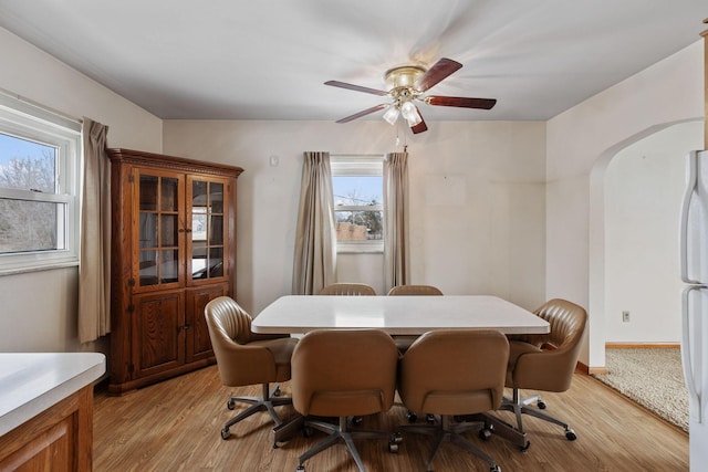 dining room featuring light wood-type flooring, baseboards, and arched walkways