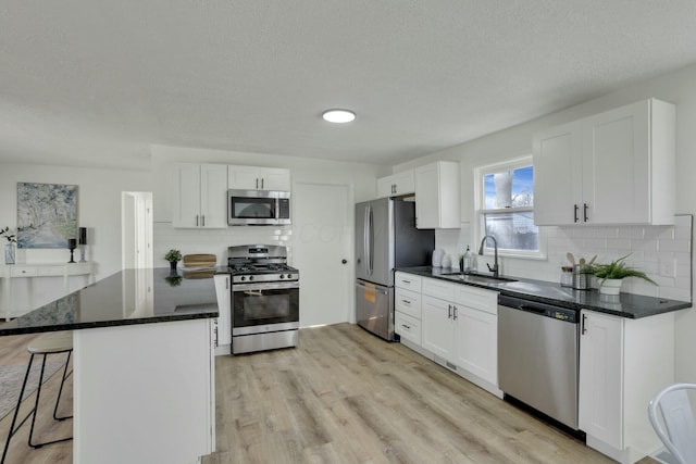 kitchen featuring stainless steel appliances, white cabinetry, a sink, and a kitchen breakfast bar