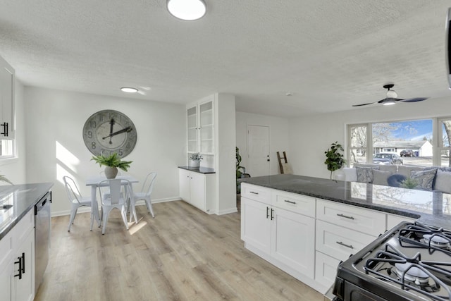 kitchen with a textured ceiling, white cabinetry, stainless steel dishwasher, light wood finished floors, and black gas range oven