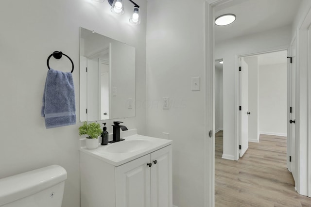 half bathroom featuring vanity, toilet, and wood finished floors