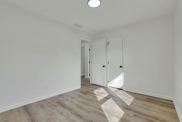 unfurnished bedroom featuring wood finished floors, visible vents, and baseboards