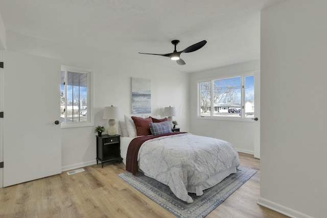 bedroom with ceiling fan, wood finished floors, visible vents, and baseboards