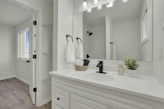 full bathroom featuring wood finished floors, vanity, baseboards, and walk in shower