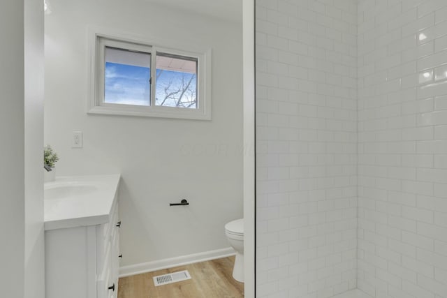 bathroom featuring toilet, wood finished floors, vanity, visible vents, and baseboards