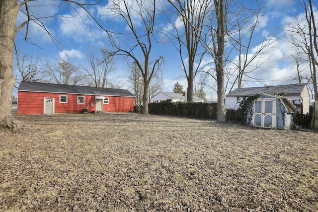 view of yard featuring a storage shed, an outdoor structure, and fence