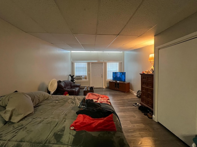 bedroom with cooling unit, a drop ceiling, baseboards, and wood finished floors