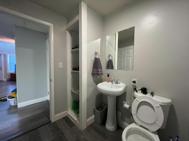 bathroom with a sink, toilet, baseboards, and wood finished floors