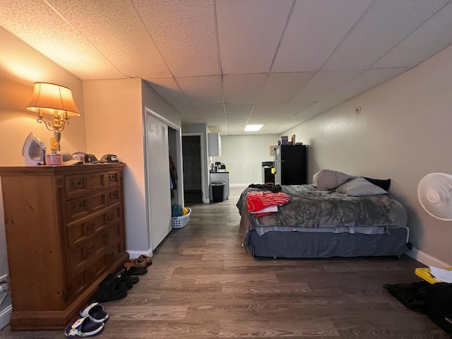 bedroom with a paneled ceiling, baseboards, and wood finished floors