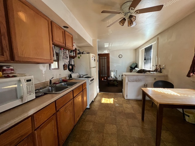 kitchen featuring ceiling fan, white appliances, a sink, light countertops, and brown cabinetry