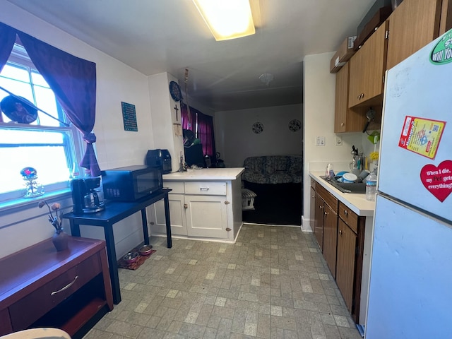 kitchen with black microwave, light countertops, and freestanding refrigerator