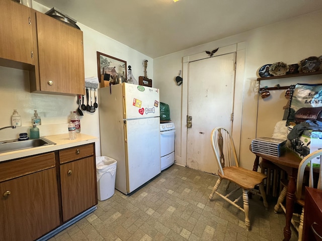 kitchen featuring light countertops, white appliances, a sink, and brown cabinets