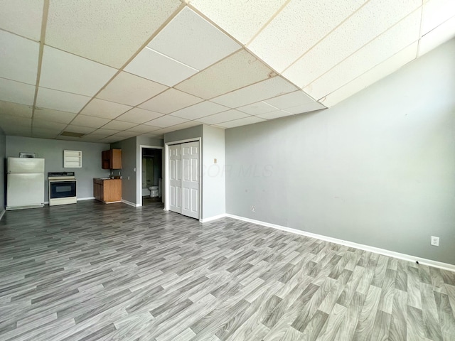 interior space featuring a paneled ceiling, wood finished floors, freestanding refrigerator, and baseboards