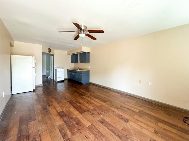 unfurnished living room featuring dark wood-style floors, a sink, baseboards, and ceiling fan