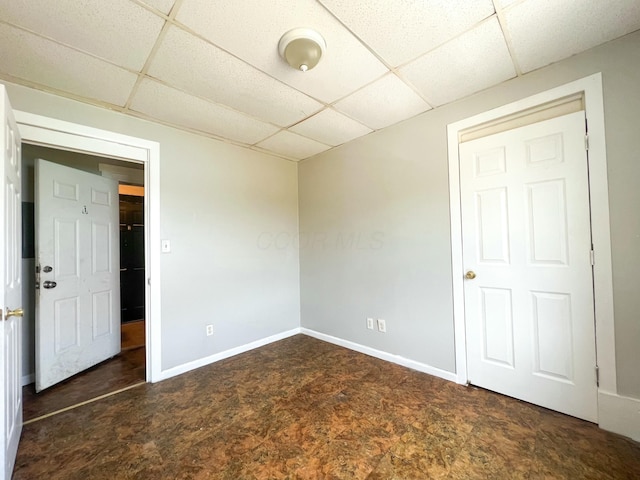 unfurnished room with a paneled ceiling and baseboards