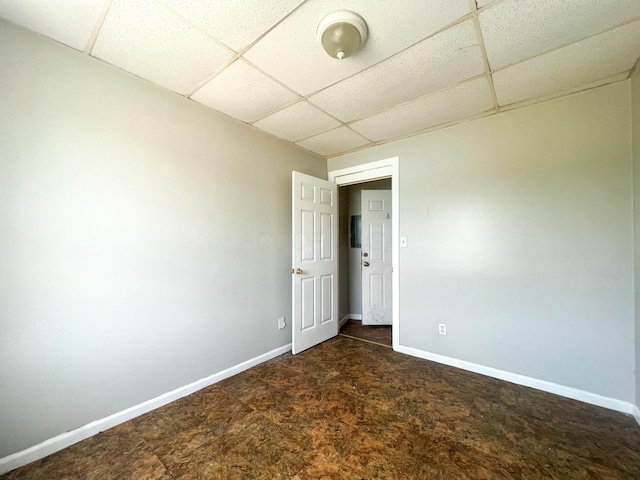 empty room with a drop ceiling and baseboards