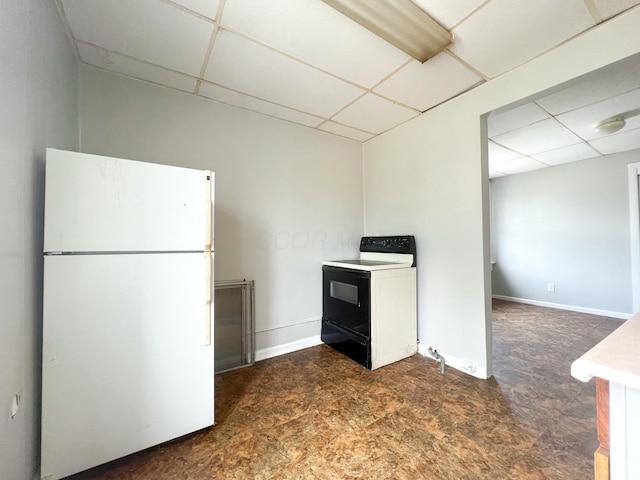 kitchen with range with electric cooktop, a drop ceiling, freestanding refrigerator, and baseboards