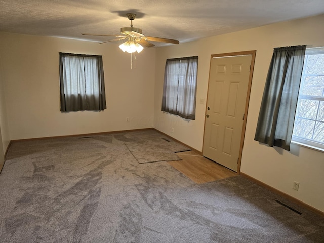 spare room featuring visible vents, ceiling fan, carpet flooring, and plenty of natural light