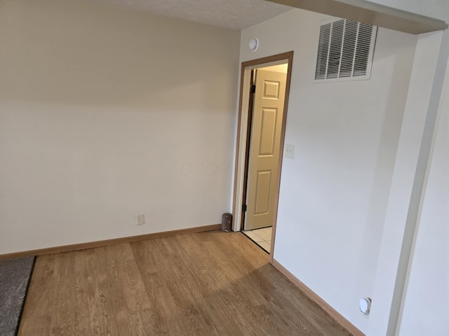 spare room with light wood-type flooring, baseboards, and visible vents