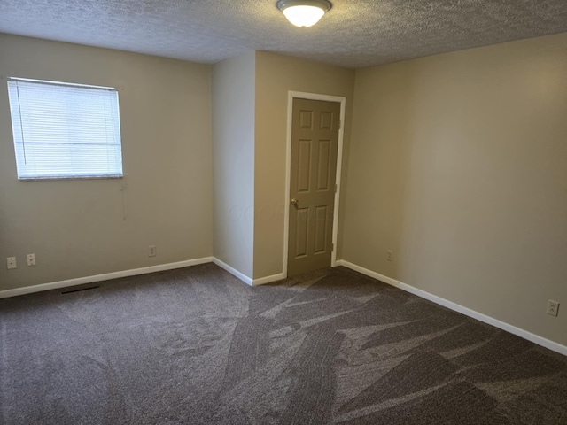 empty room featuring a textured ceiling, baseboards, and carpet floors