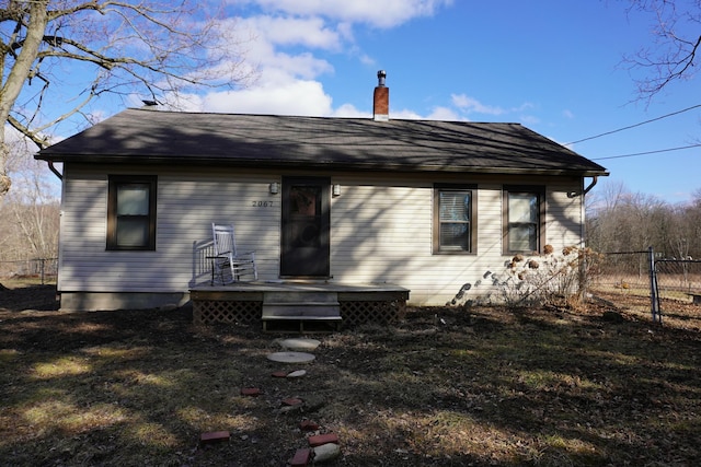 rear view of property featuring a chimney, fence, and a wooden deck