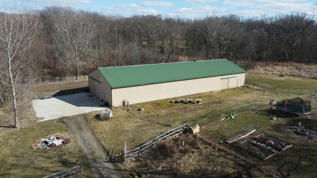 view of property exterior featuring an outbuilding, a forest view, an outdoor structure, and fence