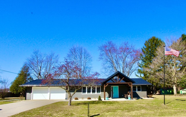 view of front of house with a garage, driveway, metal roof, and a front yard