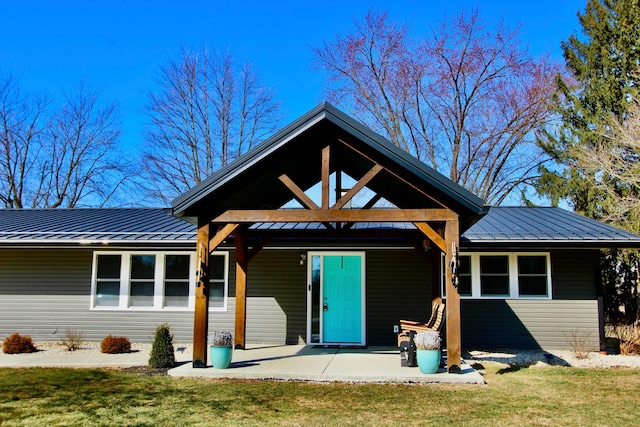 view of front of home with metal roof, a patio, a front yard, and a standing seam roof