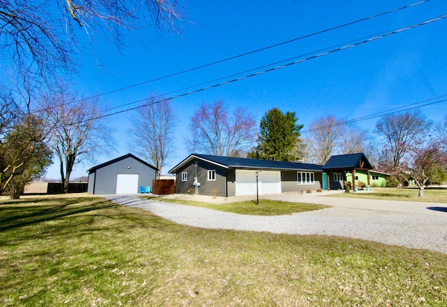 view of front of home featuring an outbuilding, a detached garage, gravel driveway, and a front lawn