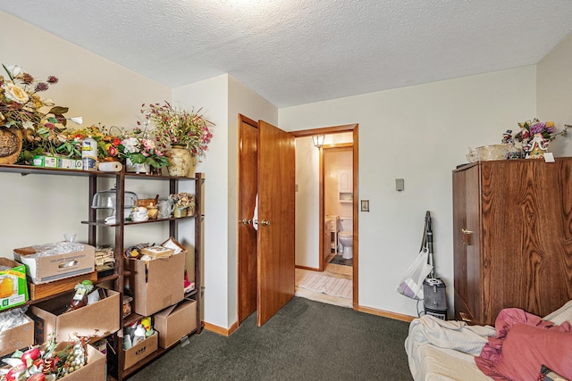 bedroom featuring a textured ceiling, carpet, ensuite bathroom, and baseboards