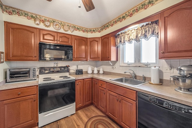 kitchen with light countertops, backsplash, a sink, light wood-type flooring, and black appliances