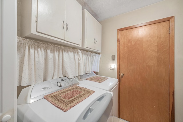 laundry area with cabinet space, a textured ceiling, and independent washer and dryer