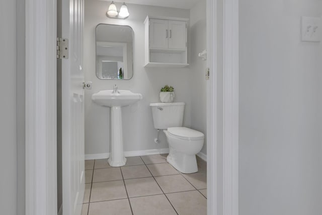 half bathroom featuring tile patterned floors, toilet, and baseboards