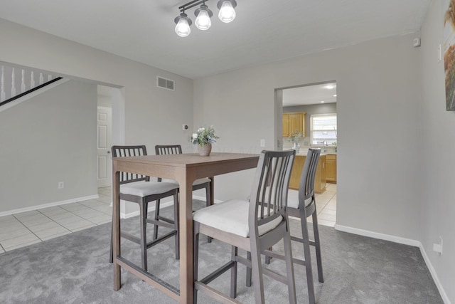 dining space with light carpet, visible vents, baseboards, and light tile patterned floors