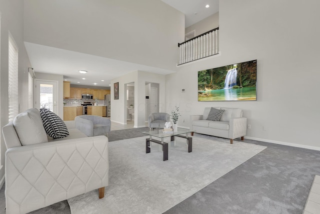 living room featuring a high ceiling, recessed lighting, light colored carpet, and baseboards