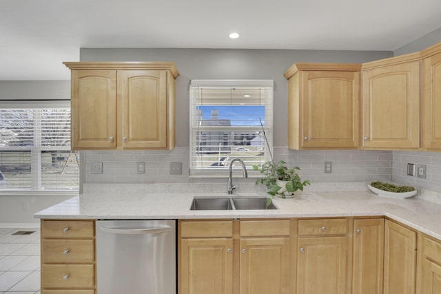 kitchen featuring light tile patterned floors, a sink, light brown cabinets, and stainless steel dishwasher