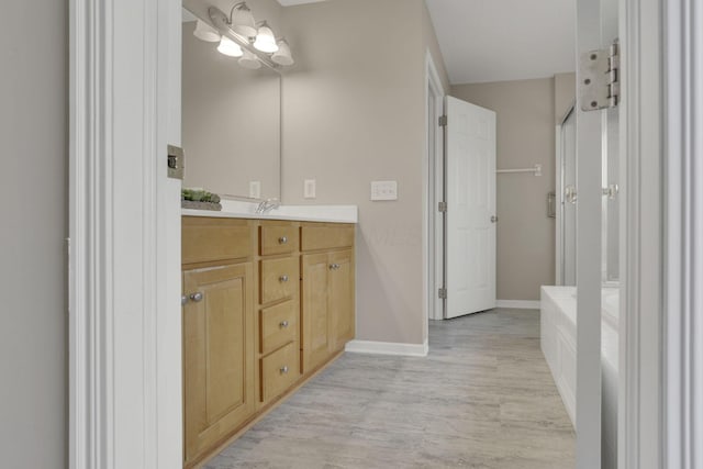 bathroom with baseboards, wood finished floors, and vanity