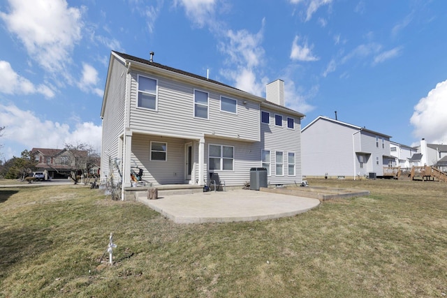 back of property with a lawn, cooling unit, a chimney, and a patio