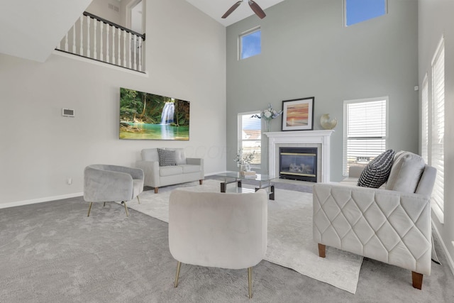 carpeted living area featuring baseboards, plenty of natural light, ceiling fan, and a fireplace