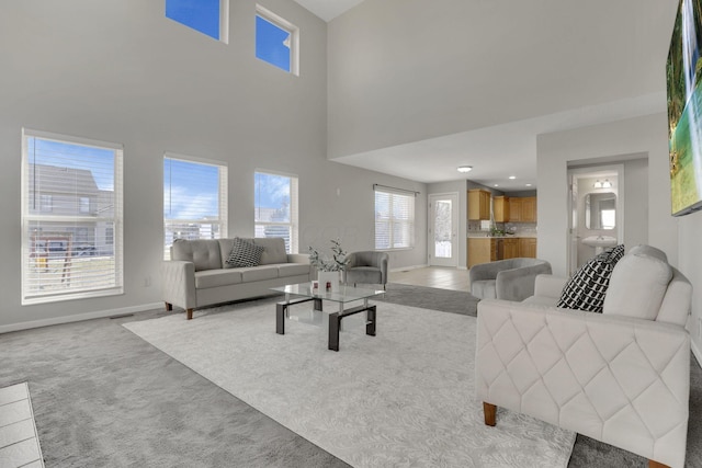 carpeted living room with a high ceiling, visible vents, and baseboards