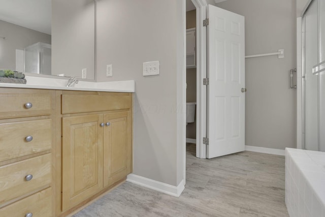 full bath featuring vanity, wood finished floors, and baseboards