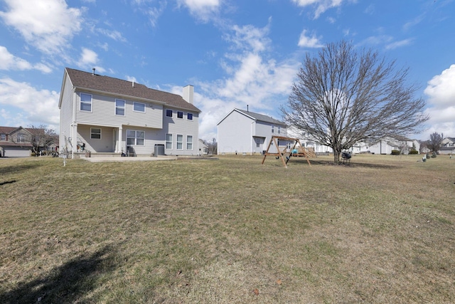 back of property with a patio area, a chimney, a playground, and a yard