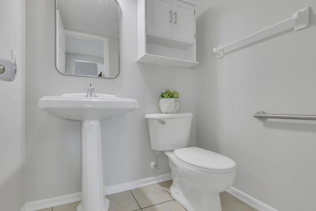 half bathroom featuring tile patterned flooring, toilet, and baseboards