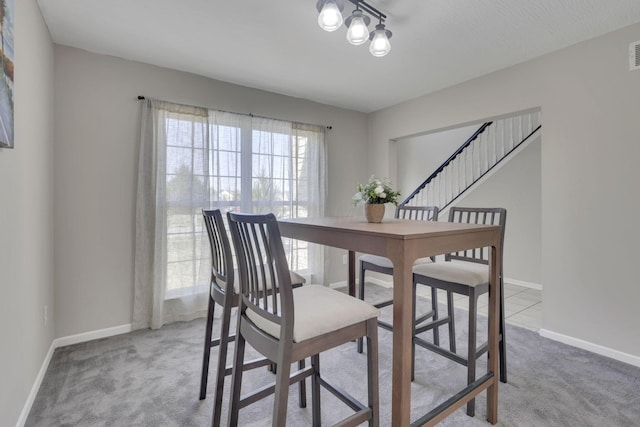 dining space featuring stairs, visible vents, baseboards, and carpet flooring