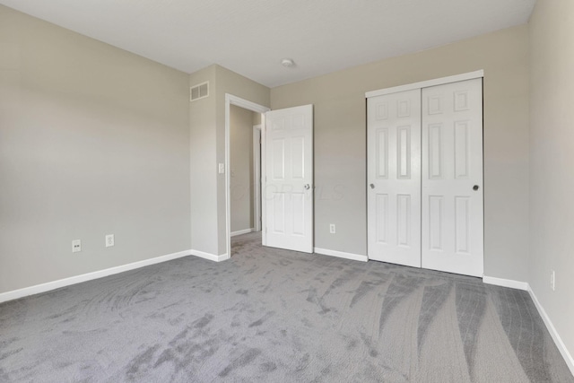 unfurnished bedroom featuring a closet, visible vents, dark carpet, and baseboards