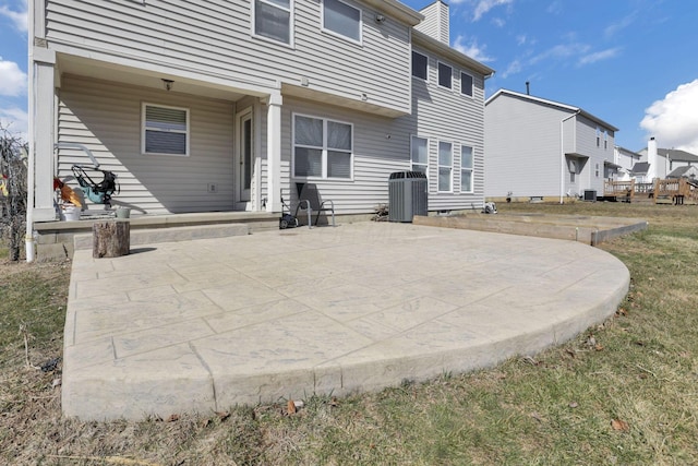 back of house with central air condition unit, a chimney, a patio, and a residential view