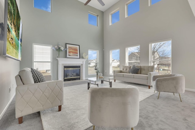 living area featuring baseboards, a ceiling fan, carpet flooring, and a tiled fireplace