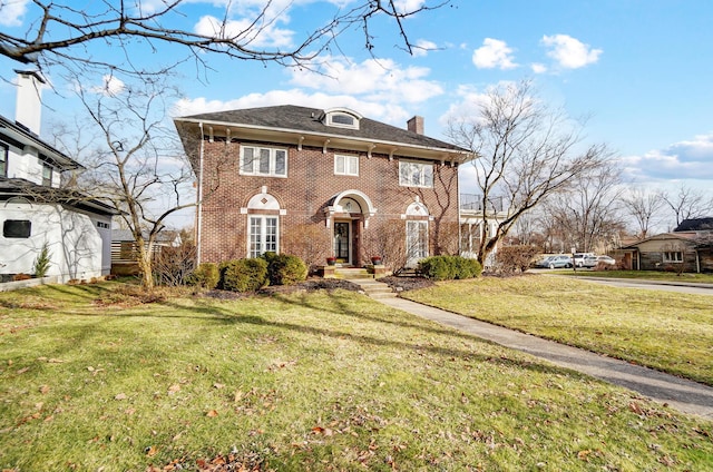 colonial inspired home featuring brick siding, a chimney, and a front lawn