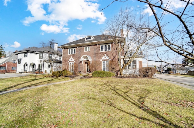 colonial-style house with a front yard, brick siding, a residential view, and a chimney