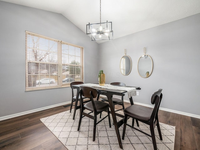 dining area with baseboards, a chandelier, vaulted ceiling, and wood finished floors